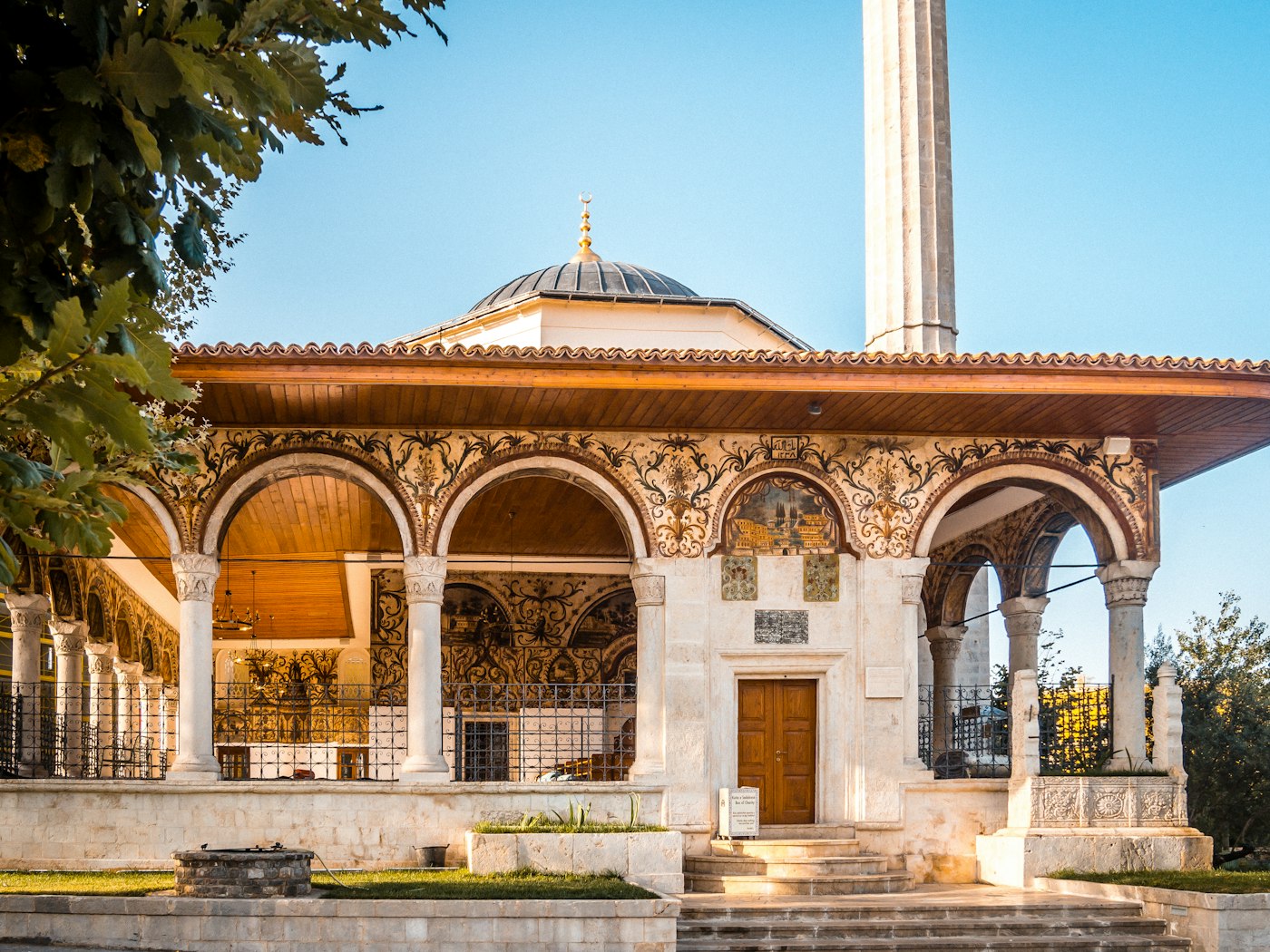 The frescoed portico, dome and minaret of the Et'hem Bey Mosque in Tirana in warm evening light